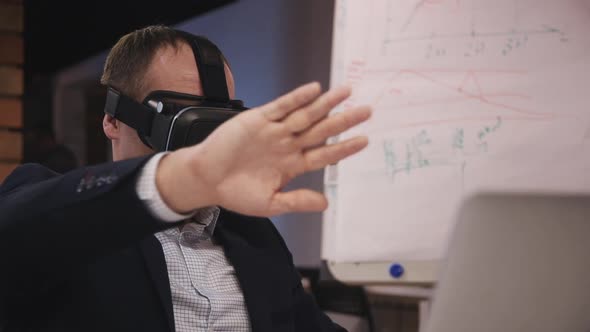 Man Wearing Virtual Reality Glasses and Sitting in Office