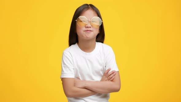 Funny Korean Little Girl Wearing Sunglasses Posing Over Yellow Background alt