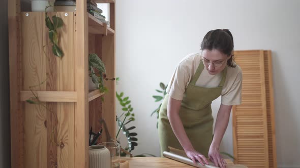 A Florist in Apron Unwraps a Craft Wrapping Paper