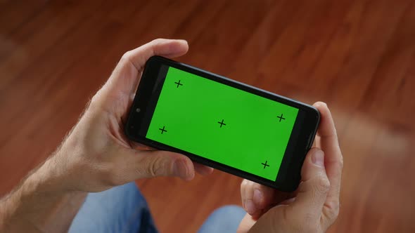 Men's Hands Holding Smartphone with Green Mock-up Screen