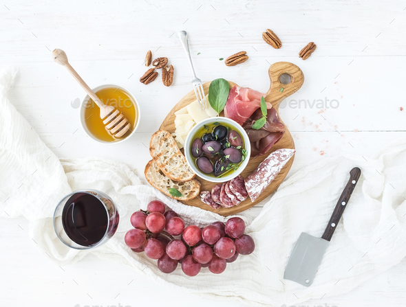 Wine appetizer set. Glass of red, grapes, parmesan cheese, meat variety, bread slices