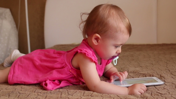 Small Kid Lying On Sofa And Playing With Tablet