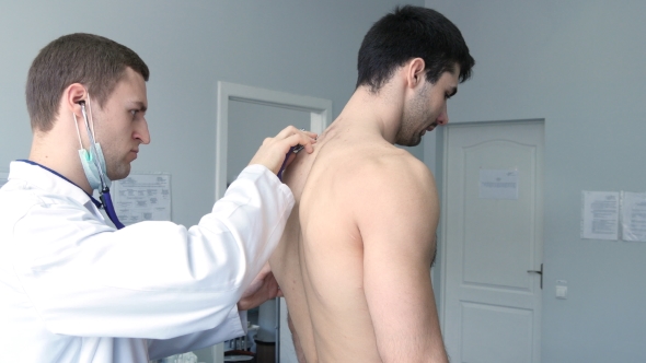 Doctor Examining Back Of Young Male Patient With Stethoscope alt