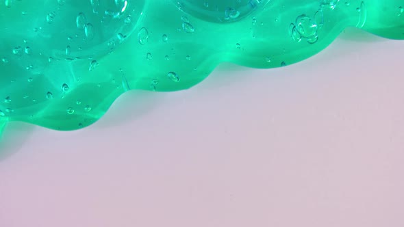 Transparent Green Gel Fluid with Bubbles Flowing Down on a White Surface alt