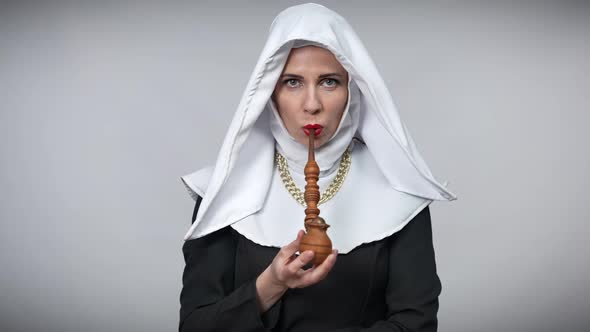 Front View of Slim Woman in Nun Costume Smoking Pipe Looking at Camera alt