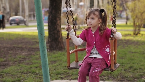 Sad Little Girl Swinging On a Swing alt