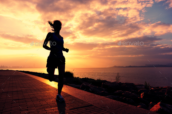 Sporty fitness woman running on sunrise seaside trail - Stock Photo - Images