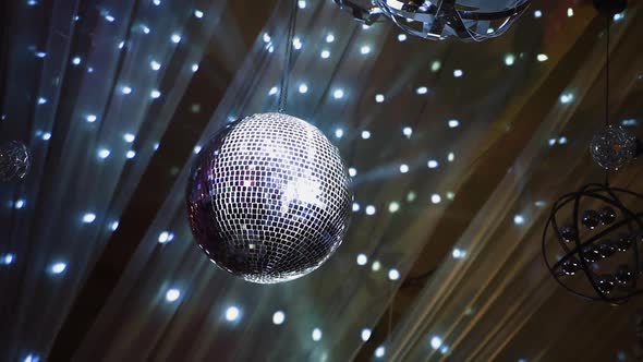 Night club ceiling with mirror ball and lights. Silver disco ball spinning against beautiful shining alt