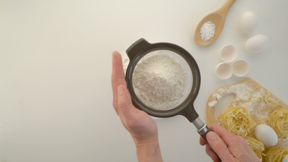Sifting Flour Through Sieve On Wooden Table
