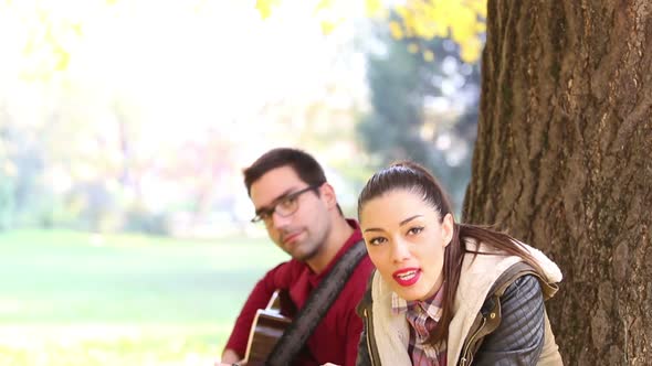Woman Singing And Man Playing Guitar While Sitting On A Tree In Park 3 alt