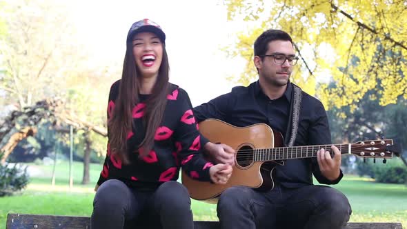 Young Brunette Woman Singing While Handsome Man Playing Guitar alt