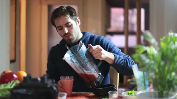 Man Pouring Fruit Smoothie Into Glass And Drinking It alt