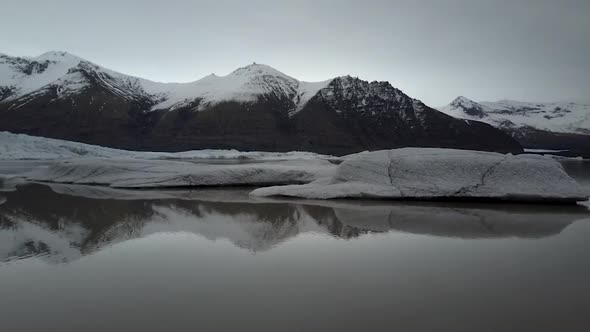 Aerial snowy mountains reflected on the ocean's water