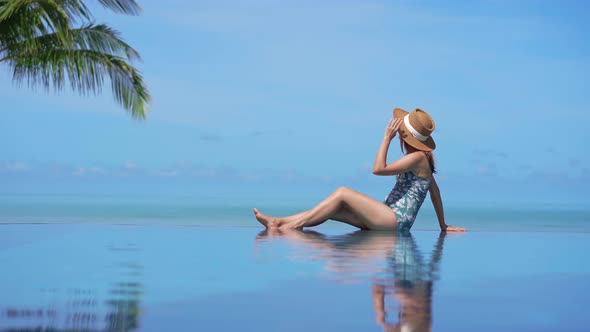 Young woman traveler relaxing and enjoying by a tropical resort pool while traveling