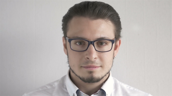 Portrait Of Attractive Young Man With Glasses Standing On Gray Background alt