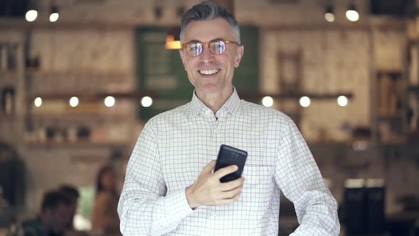 Man with mobile phone standing in the coffee shop.