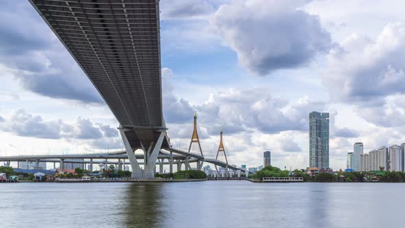 Large suspension bridge over Chao Phraya river with cargo ship, zoom in - time lapse