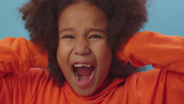 Pretty African American girl closes her ears with hands and screaming 'no' alt