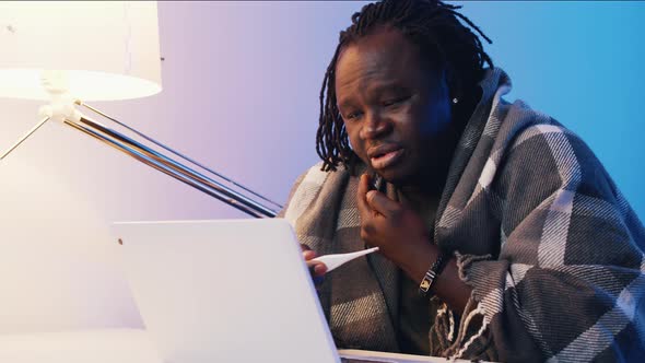 Man with Thermometer Wrapped in the Blaked Having Online Doctor Consultations alt