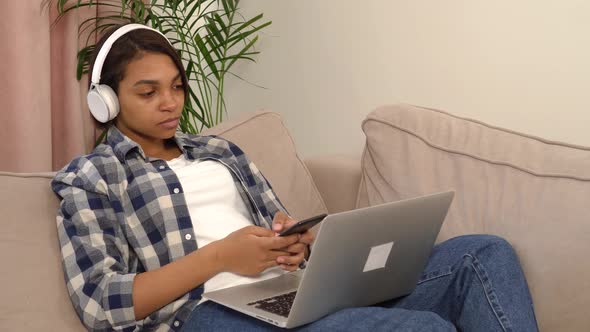 A Woman Using a Silver Laptop and Smartphone While Lying on the Couch