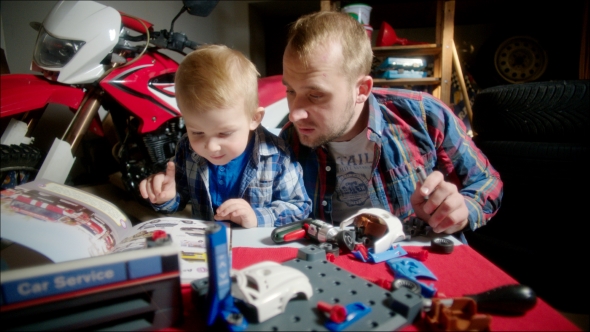 Father And Son Assembling Toy Car Using Manual Book