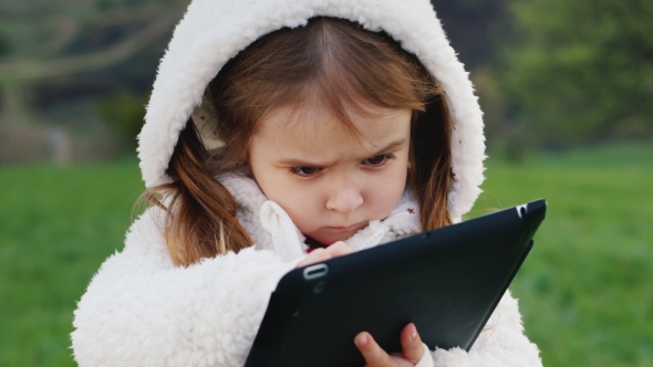 Very Serious Girl 3 Years Old With a Tablet alt