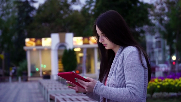Girl Sitting On a Bench In The Park And Use Applications In The Computer Tablet alt
