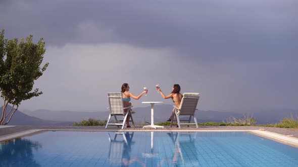 Women Drinking Cocktails By Swimming Pool with Panoramic Mountain View