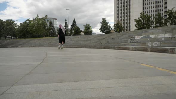 A Girl in a Long Black Dress Rides Her Back Forward on Roller Skates