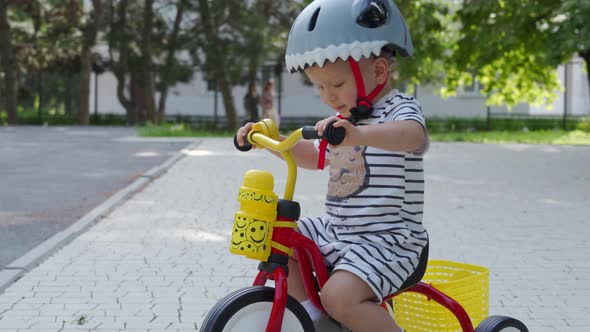 Mother Teaching Little Child to Ride Tricycle for Kids Outdoors Toddler Boy in Funny Bike Helmet alt