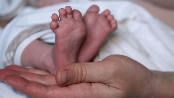 Mother's Hands Stroking Newborn's Baby Feet 