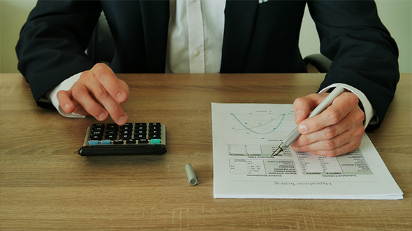 Businessman Checks the Calculations on a Calculator in the Office