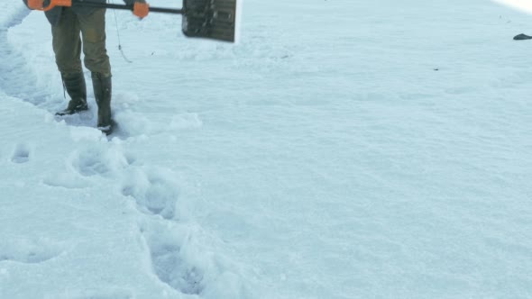 Man Cleaning Snow From Pavement