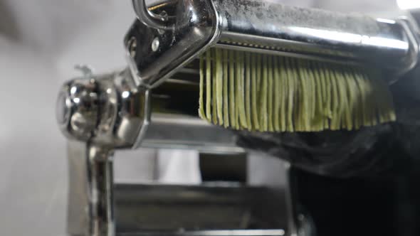 Traditional Italian Cuisine. Making Homemade Pasta, Close-up of Chef Makes Pasta Using Steel Machine alt