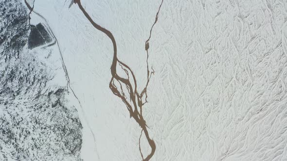 Drone Over Snow Covered Landscape With Frozen Braided Riverbed alt