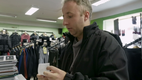 Man Shopping For Clothes And Speaks To Cashier