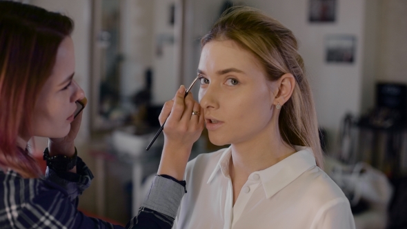 Girl Stylist Working In a Beauty Studio. Make-up For a Beautiful Blonde. Working With Shadow alt