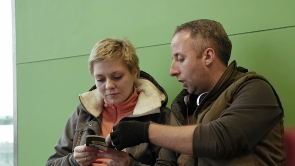 Couple Waiting At Airport Terminal With Tickets