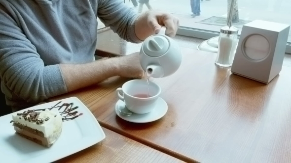 Man Pours Tea From Teapot Spills And Wipes Table