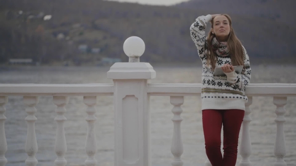 The Young Beautiful Woman Is Standing On The Quay With The Tablet Pc In Her Hands.