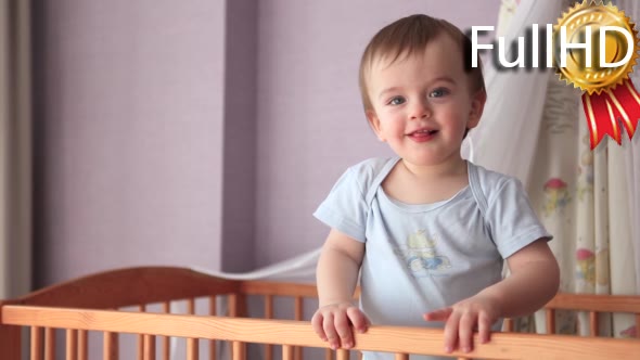 Baby Boy Standing in Cot and Showing Tongue