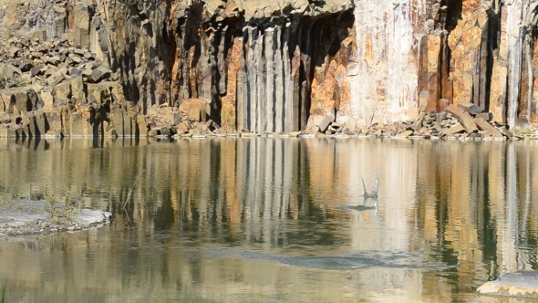 Stone Skipped On Smooth Water Surface On Background Of Cliffs