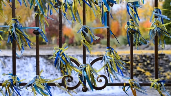 Blue And Yellow Ribbons Tied To An Iron Fence Blown By Wind