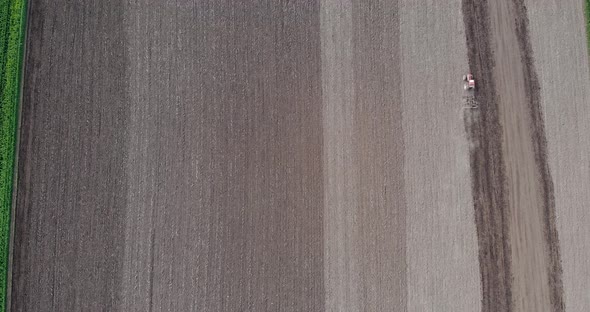 Agricultural Tractor Working And Cultivate Fields For Crops In Countryside. - aerial alt