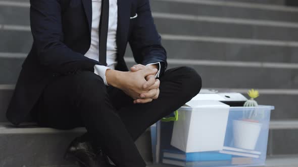 Sad Businessman Sitting on Stairs Outdoor With Box of Stuff as Lost Business