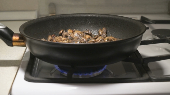 The Mix Of Mushrooms Is Fried In a Black Pan alt