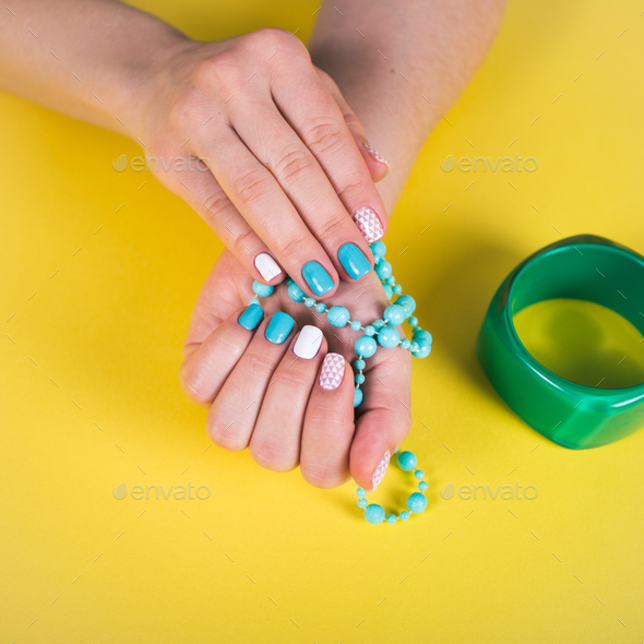 beautiful manicure. gel polish coating in white and turquoise, stamping. Stock Photo by ollinka