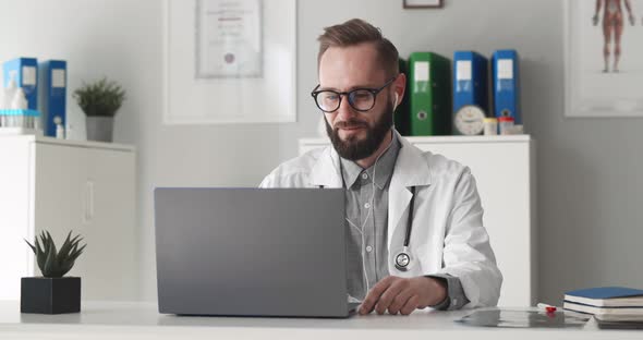 Doctor in White Medical Uniform and Headphones Talk on Video Call on Computer Consult Patient Online alt