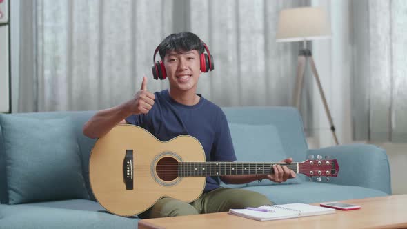 Asian Boy Composer With Headphones Smiling And Showing Thumbs Up Gesture To Camera alt