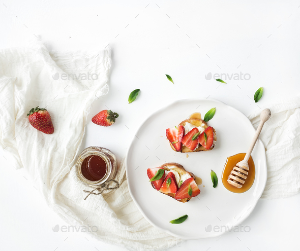 French toasts with strawberry, cream cheese, honey and mint on light ceramic plate